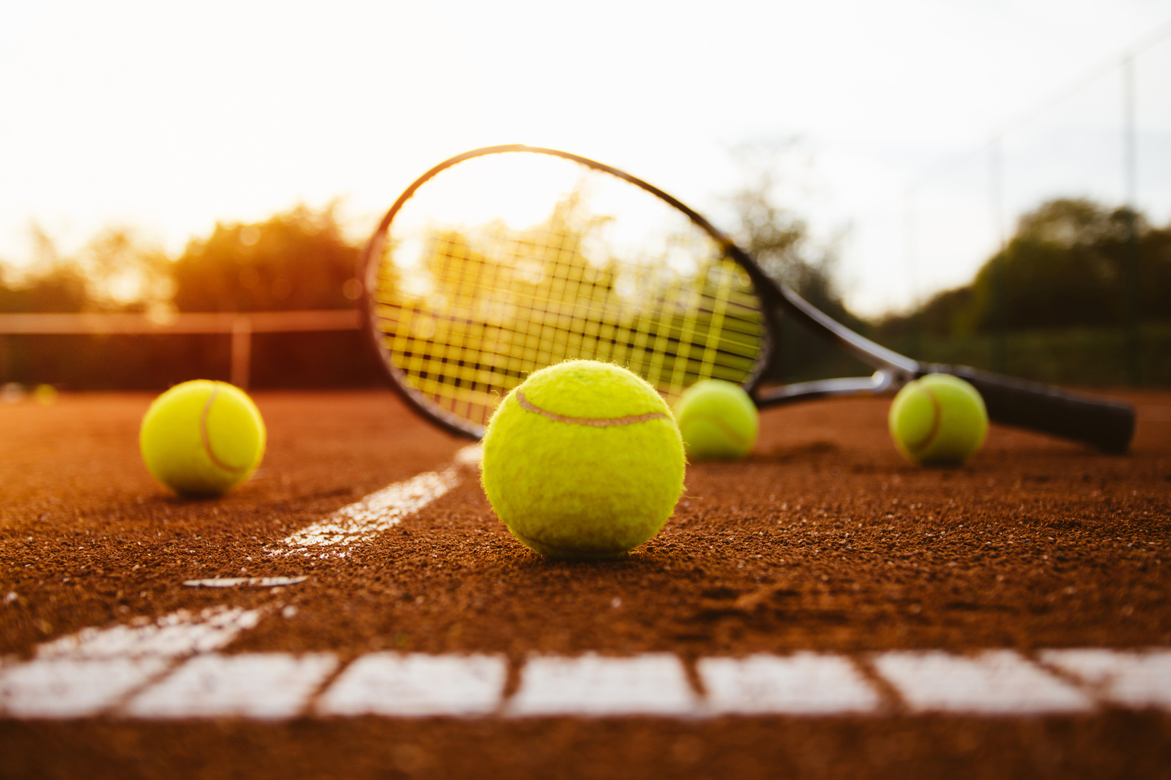 Tennis balls with racket on clay court